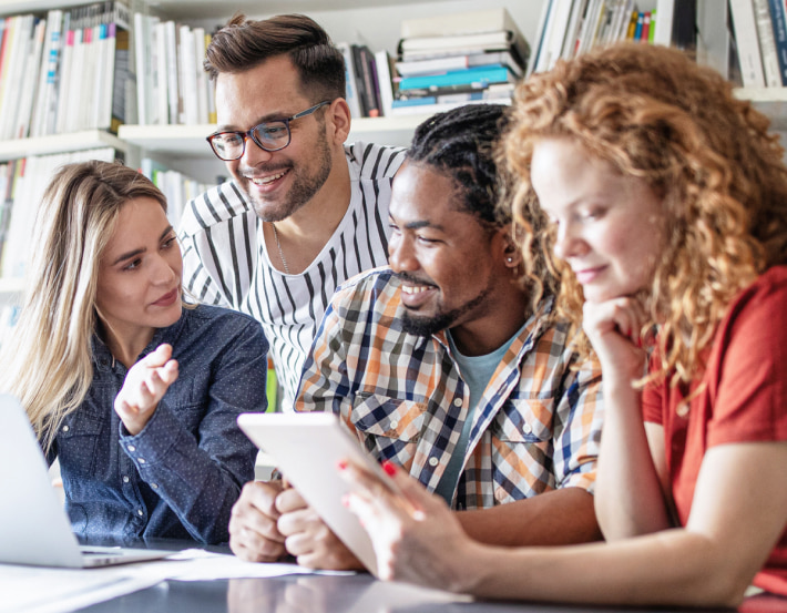 Grupo de jovens reunidos conversando sobre trabalho em uma mesa do escritorio