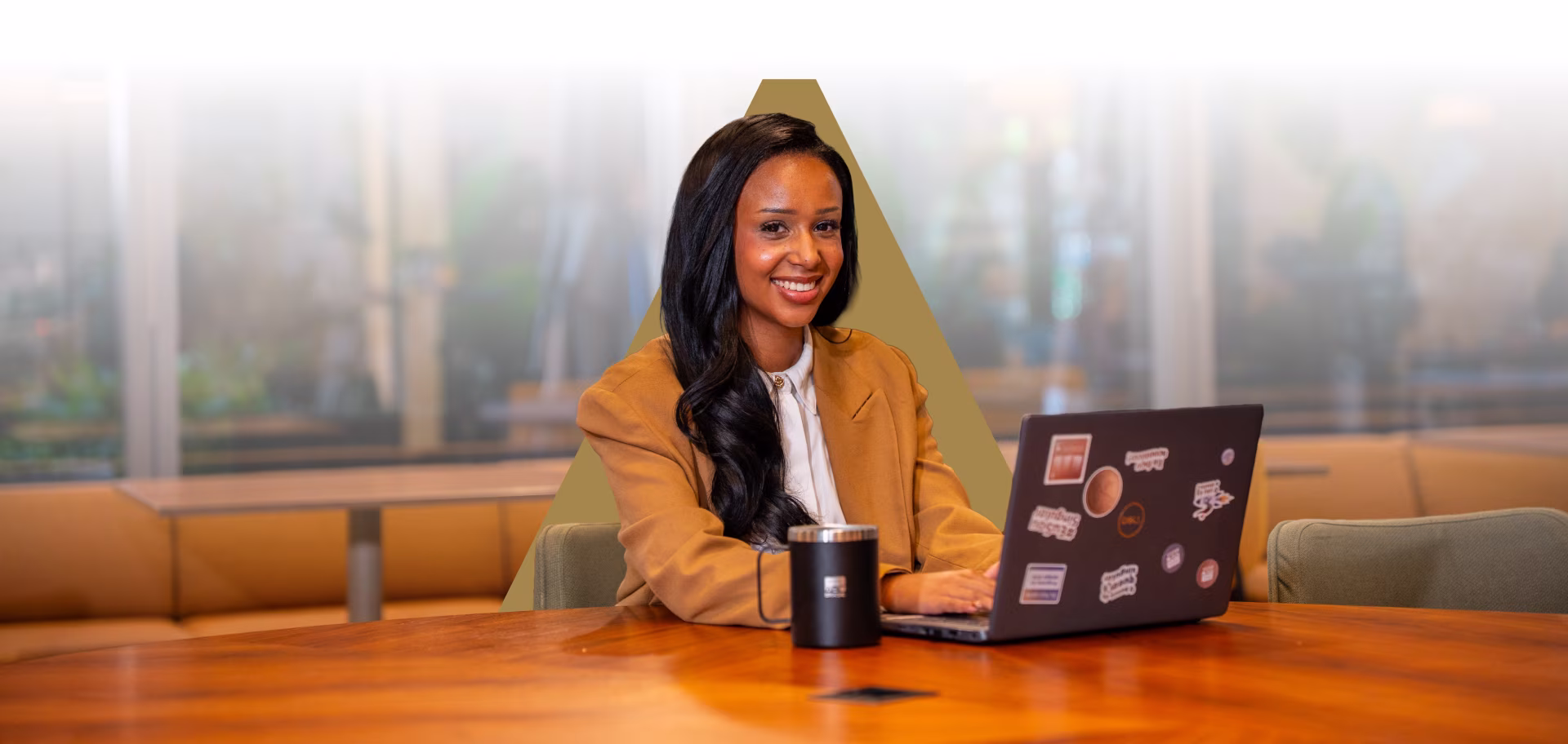 Uma jovem de cabelo curto sorrindo enquanto utiliza notebook no escritório