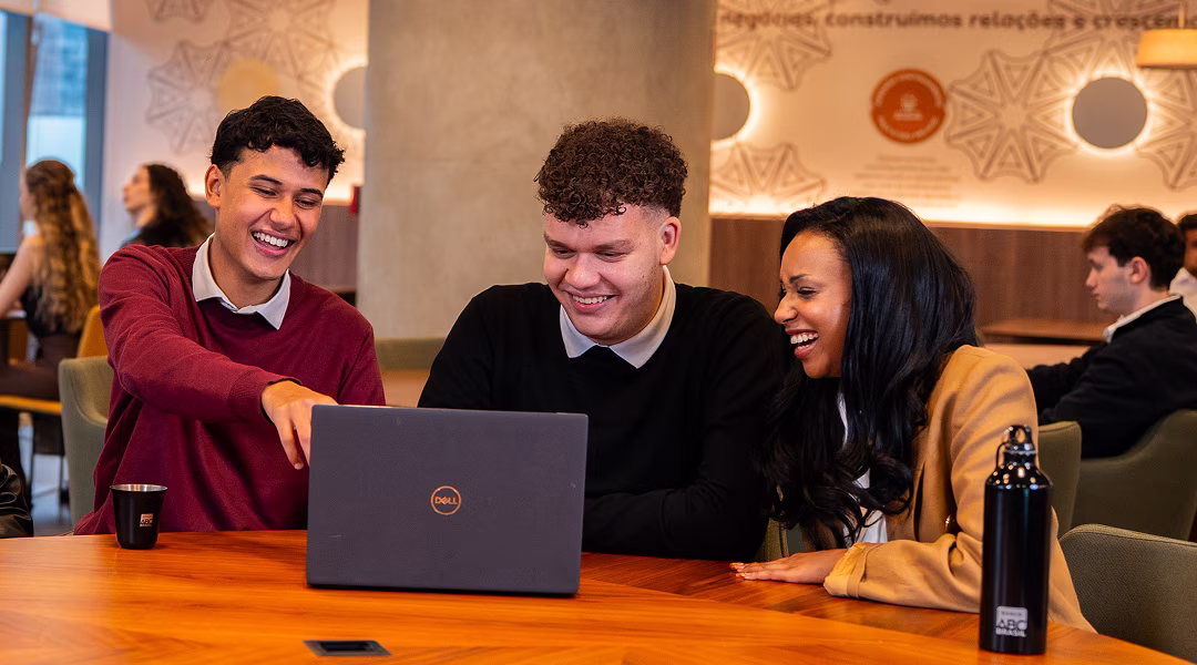 Estagiárias sorrindo enquanto utilizam notebook