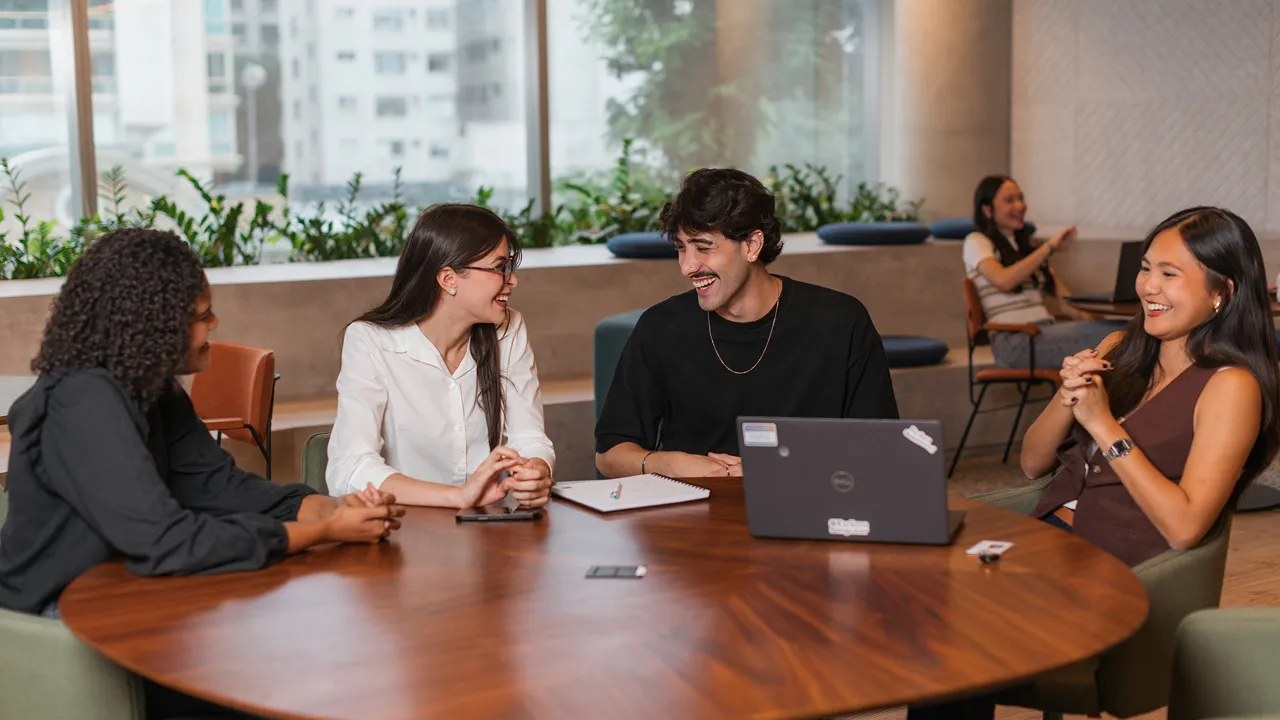 Estagiários sentados em uma mesa redonda no escritório