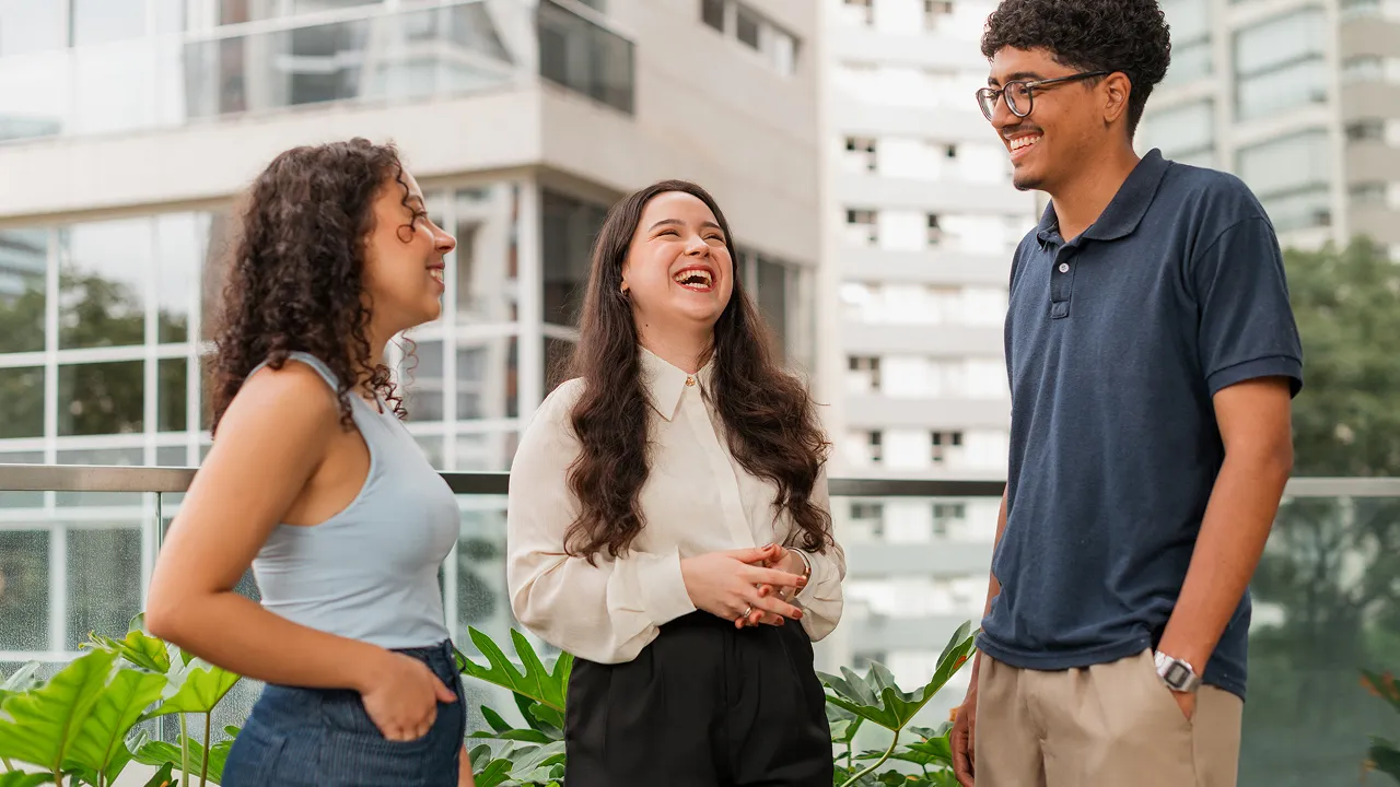 Jovens sorrindo na parte de fora do prédio do Banco ABC