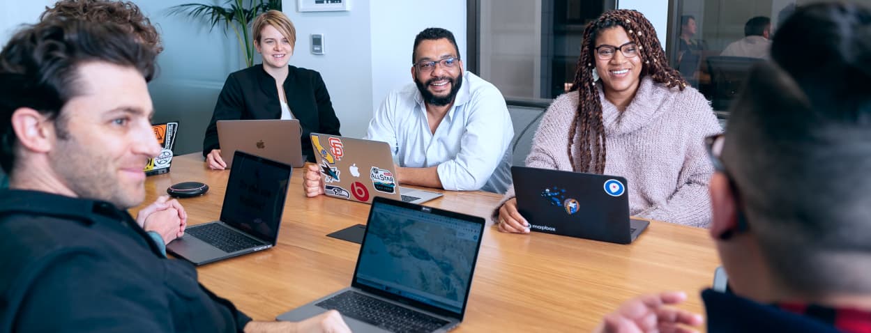 Pessoas reunidas em uma mesa fazendo uma reunião