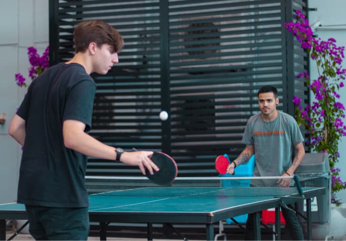Dois funcionários jogando ping pong dentro da empresa