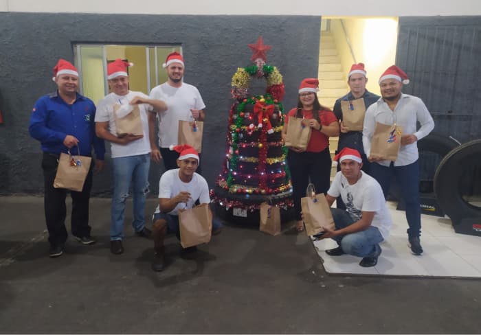 Equipe trocando presentes de natal, todos utilizando um gorro de papai noel