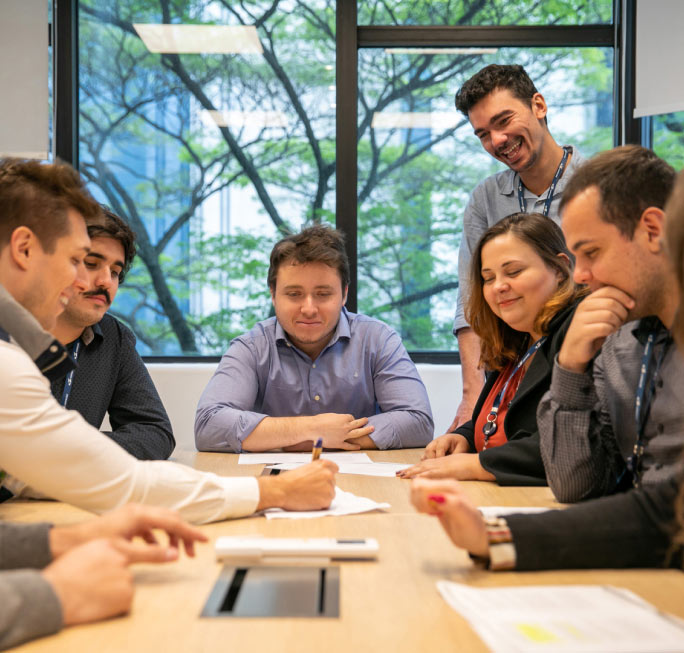 Gestores e estagiários em uma mesa fazendo reunião