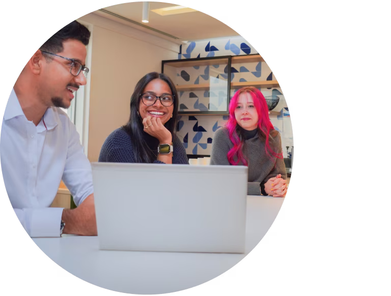 Equipe diversa da Danone reunida em torno de um notebook no escritório.