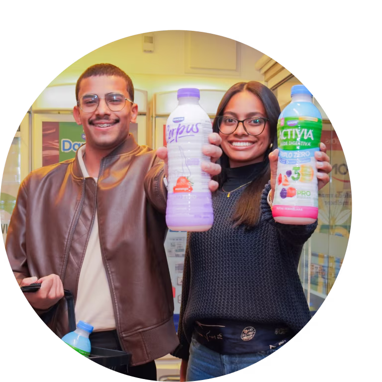 Profissionais da Danone seguram bebidas lácteas e sorriem em um ambiente colaborativo.