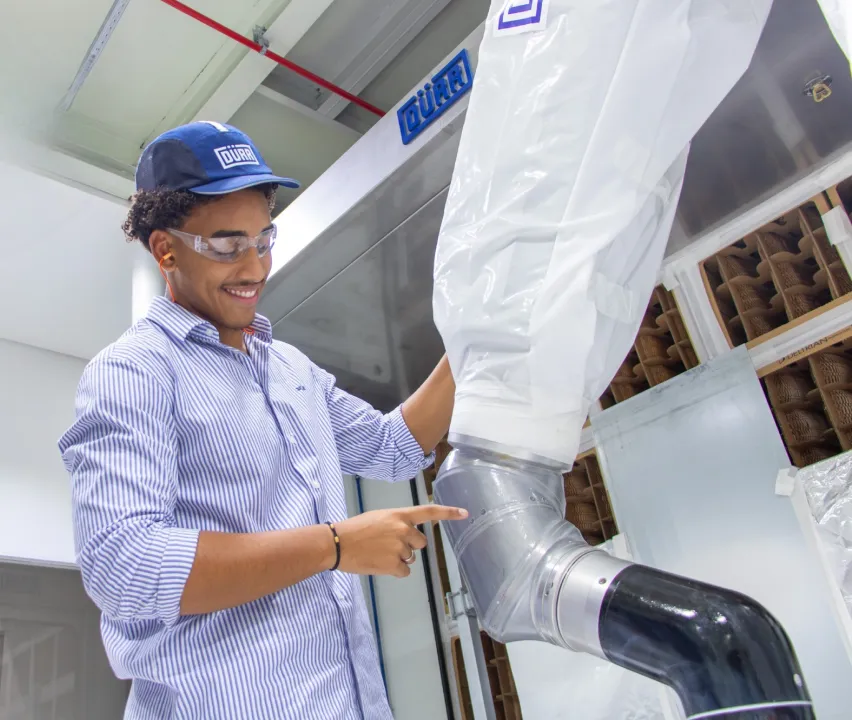 Jovem sorrindo enquanto trabalha na fábrica