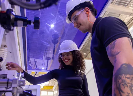 Jovens sorrindo e analisando equipamento na fábrica