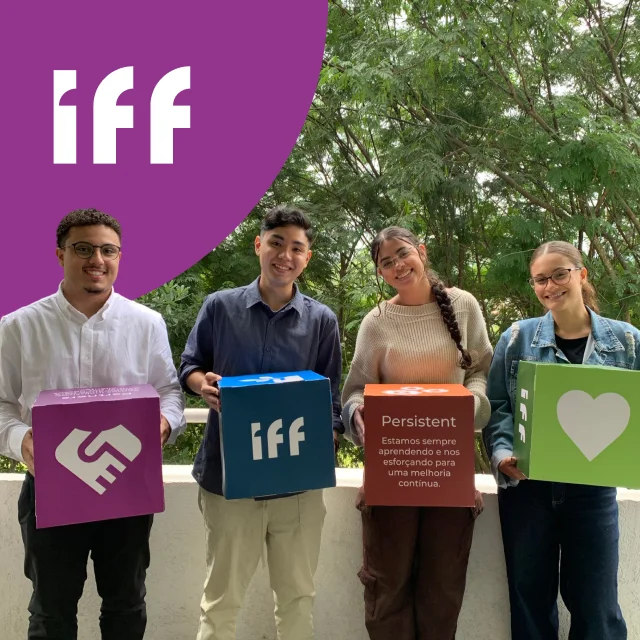 Estagiários sorrindo e segurando caixas com os valores da IFF