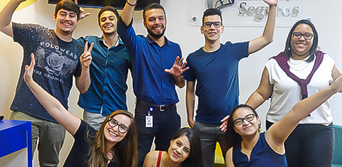 Grupo de jovens que trabalham na Liberty Seguros sorrindo e felizes posando para a foto