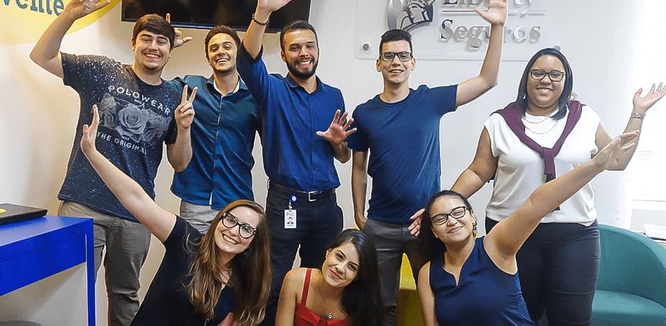 Grupo de jovens que trabalham na Liberty Seguros sorrindo e felizes posando para a foto