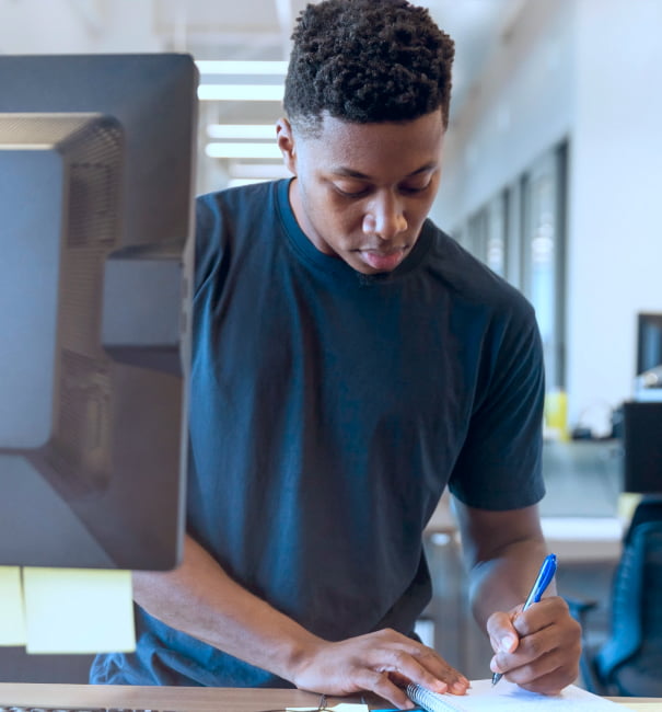 Jovem estagiário no escritório escrevendo no caderno