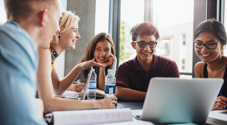 Grupo de funcionários sorrindo, trabalhando em mesa com laptops