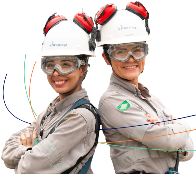 Duas jovens sorridentes utilizando uniforme e equipamentos de EPI oculos de proteção e capacetes de proteção junto com um uniforme bem robusto voltado a segurança do trabalhador