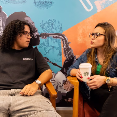 Estagiários conversando enquanto segura copo do Starbucks