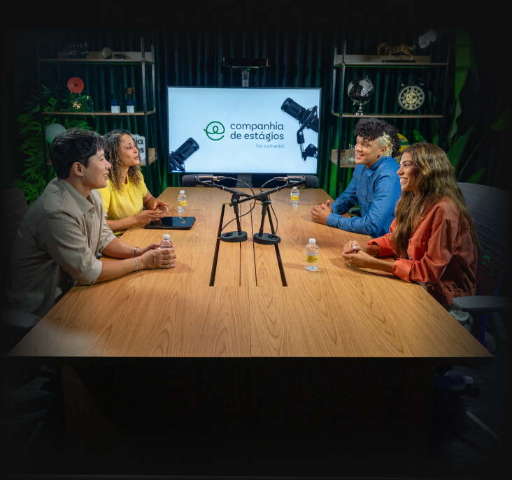 Quatro pessoas em um estúdio de podcast ao redor de uma mesa com microfones. Tela ao fundo exibe a marca Companhia de Estágios