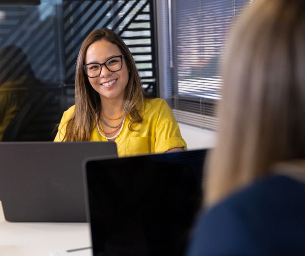 Brunette woman in business attire and glasses smiling