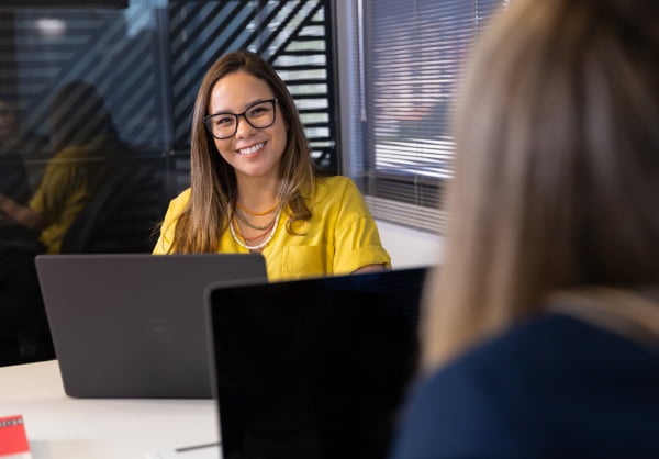 Duas mulheres usando o computador e sorrindo