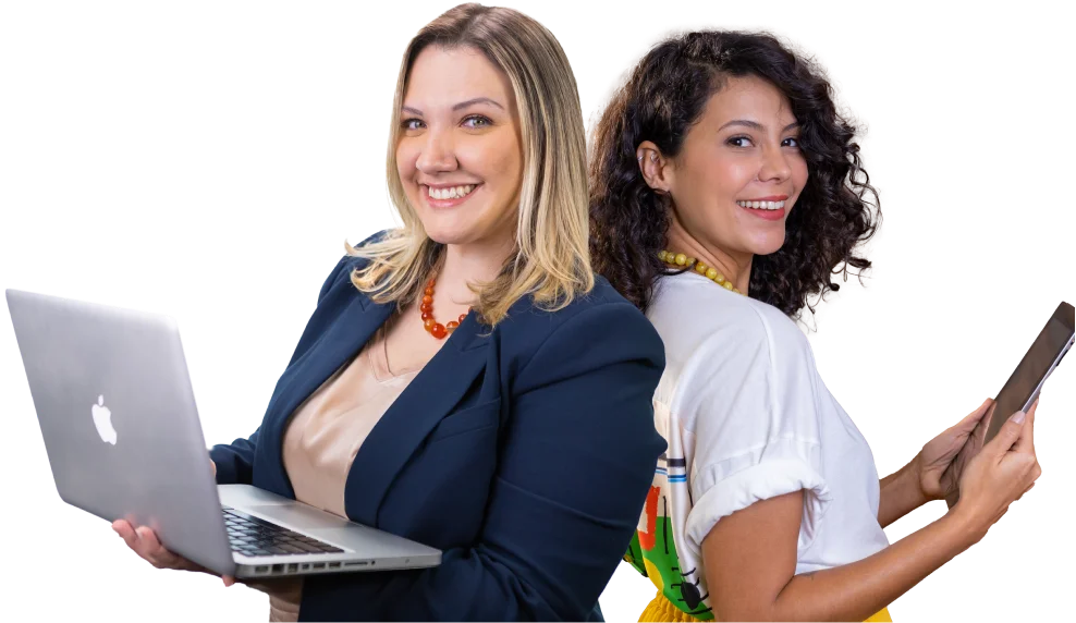Two young women back to back, one holding a laptop and the other holding a tablet