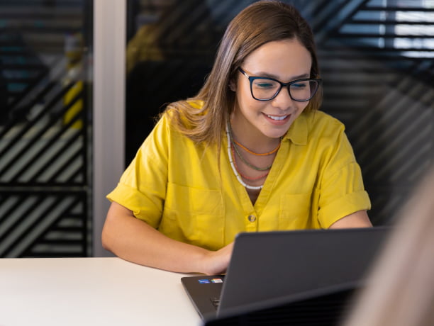 Estagiária sorrindo enquanto usa o computador