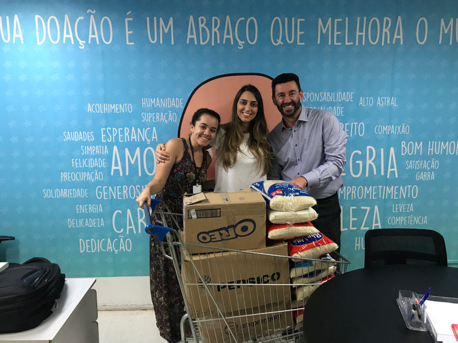 As analistas de RH da Companhia de Estágios Bruna Romano (esq.) e Raquel Oliveira (dir.) entregam doação a Vagner Carvalho (centro), superintendente da Fundação Criança, instituição mantenedora do ITACI/Arquivo Pessoal